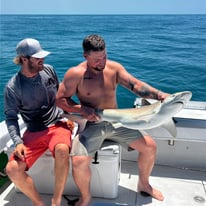 man holding a shark on a boat
